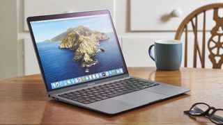 En MacBook Air (2020) står på öppnad på ett skrivbord bredvid en kaffekopp.