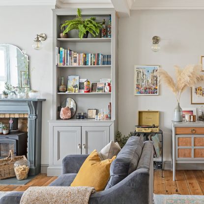 Long living room with freestanding bookshelves, period fireplace, sideboard and blue grey seating
