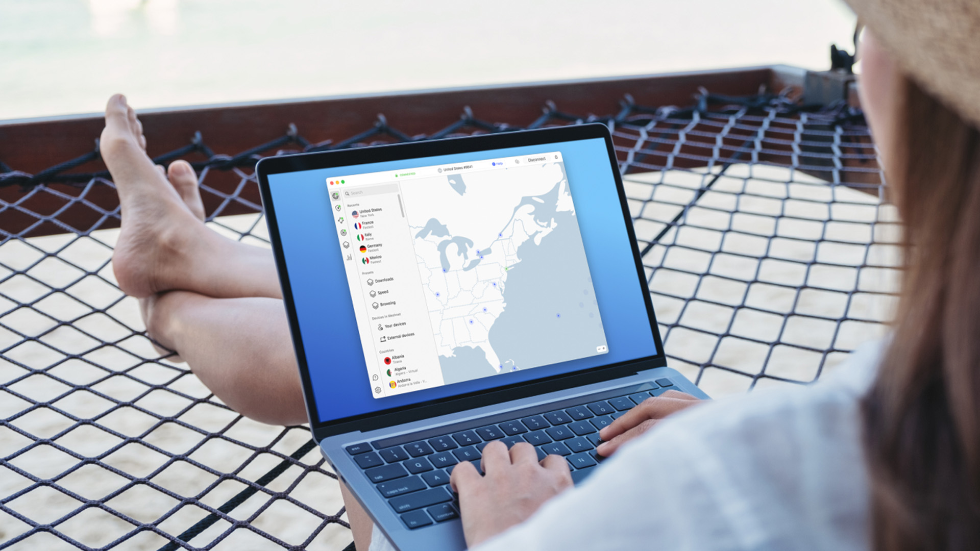 Someone sits on a net seat while typing on a laptop, which displays NordVPN on a screen