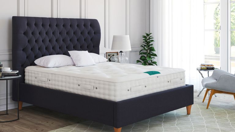 large double bed with blue headboard and frame and a bare mattress and pillows