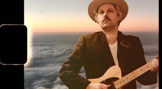 A portrait of Jim Oblon superimposed against a sky-high background as the sun is setting, the margins of the image look like an old photographic negative. Oblon wears a wide-brimmed hat and plays a Telecaster.