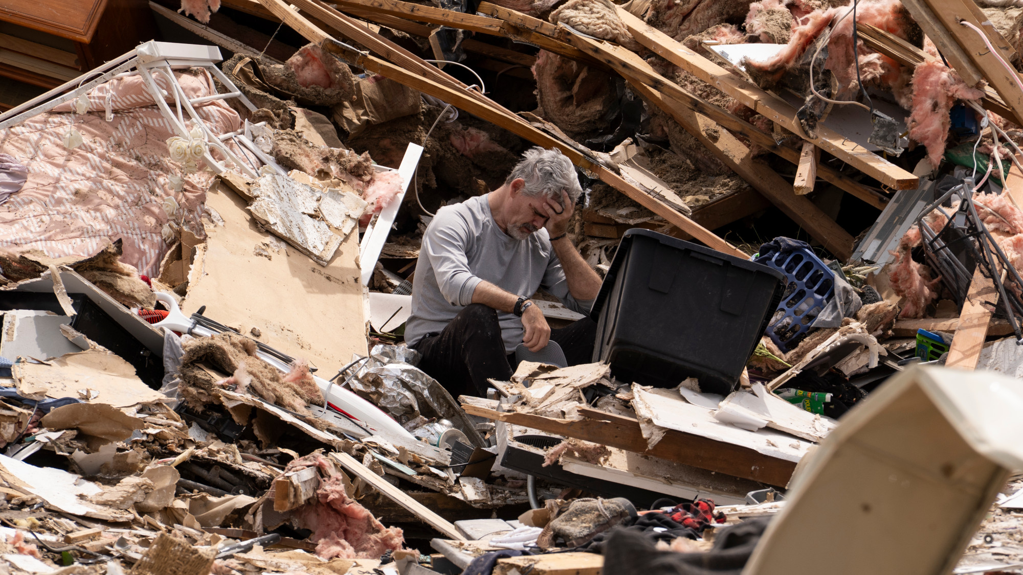 A man collects the debris from his house after it was hit by a tornado