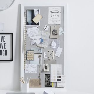 White framed pin board against white wall with notices pinned to it