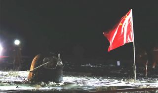 A capsule on the ground next to a Chinese flag