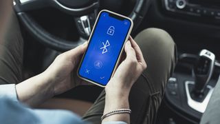 Woman accessing bluetooth on mobile phone in car