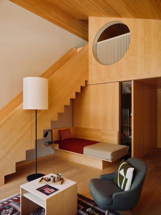 An imaginatively designed hotel room features woody, minimalist architecture characterized by geometric lines and furnishings equally inspired by Japanese style decor, Scandinavian style, and Bauhaus.