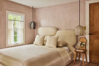 A pale pink bedroom with abstract headboard