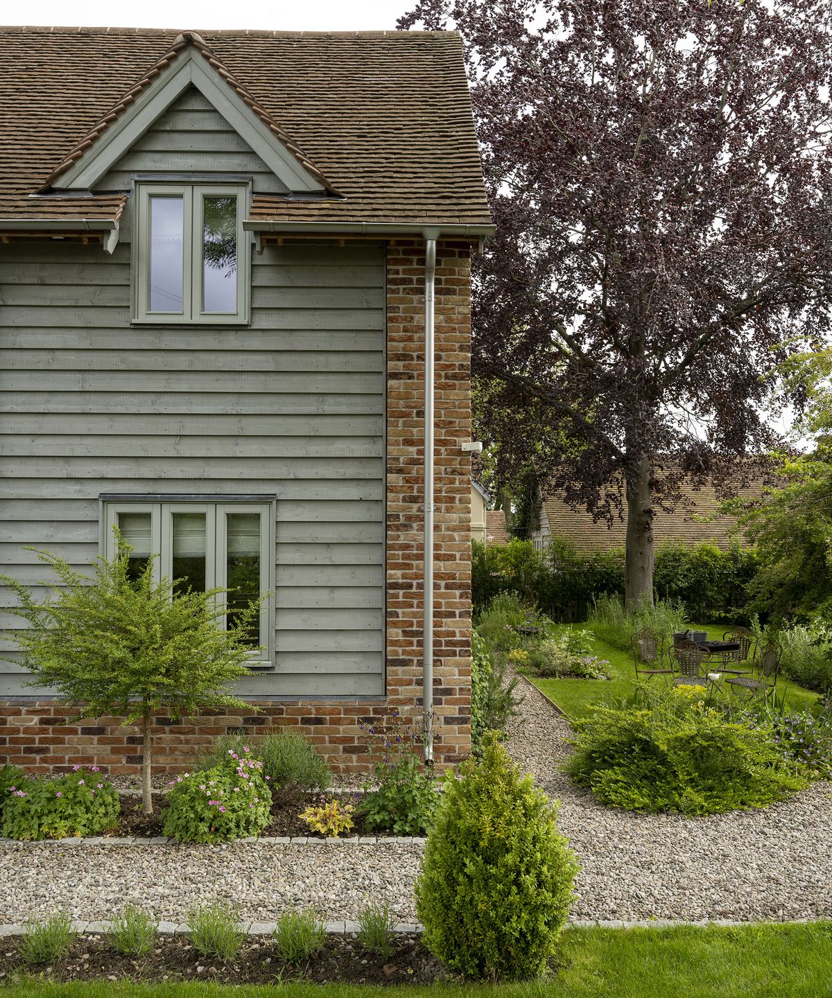 Exterior of a two storey oak frame house with brick and wood cladding with gravel pathway