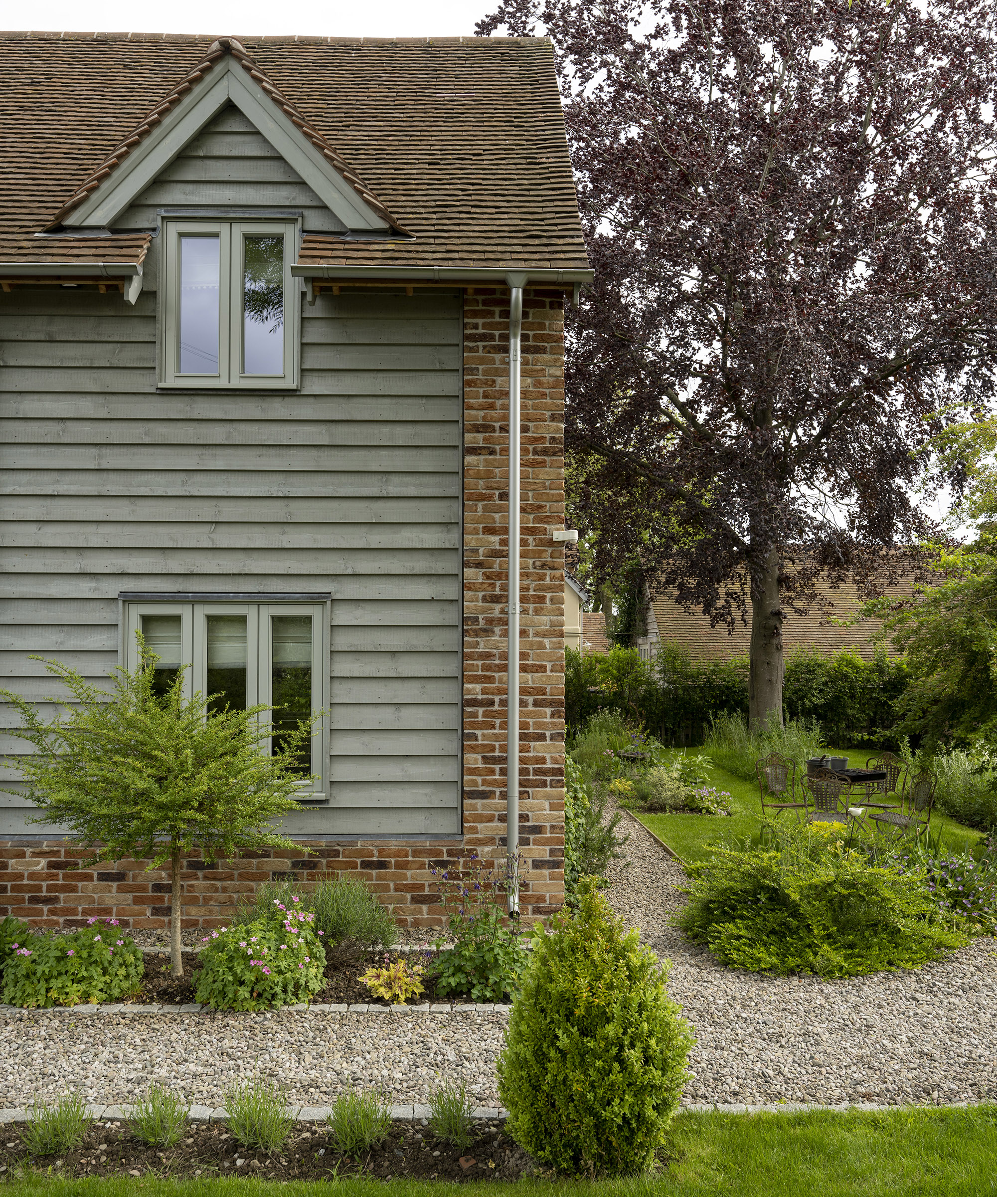 Exterior of a two storey oak frame house with brick and wood cladding with gravel pathway