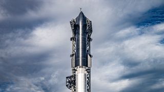 closeup of a black spacecraft atop a silver rocket, with cloudy skies in the background.