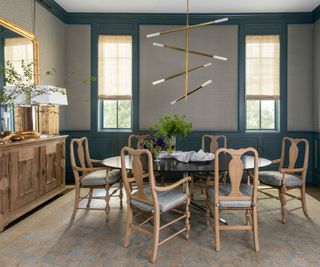 dining room with teal wainscoting and pale wood chairs and buffet with contemporary light