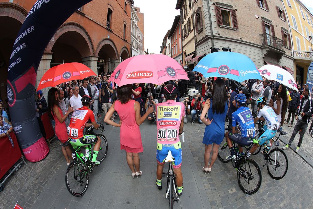 The jersey wearers sit under their umbrellas at the start