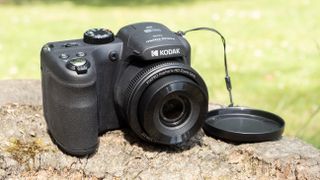 Kodak PixPro AZ255 digital camera in black on a stone surface in front of a green background outside