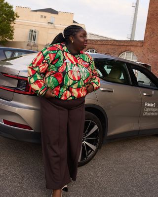 Abi Marvel wearing brown trousers and a colorful top.