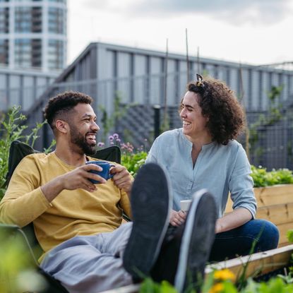 A man and woman laugh in a rooftop garden