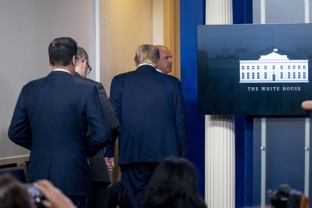 Donald Trump is escorted out of the White House briefing room.