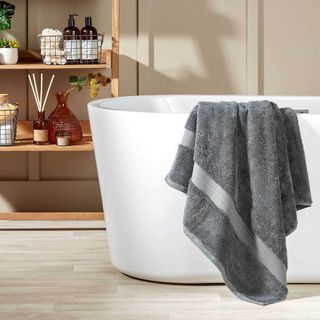 A dark grey Christy towel draped over a freestanding bath