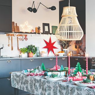 A black kitchen decorated for Christmas with lights and a set Christmas table