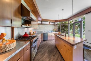 An angular shaped kitchen with built in light wooden cabinetry and a kitchen island