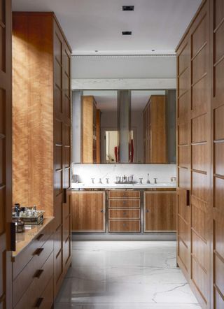 A bathroom with polished wooden cabinetry and white marble floors