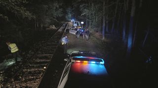 Cop cars with lights on at night by train tracks in Unsolved Mysteries Volume 3