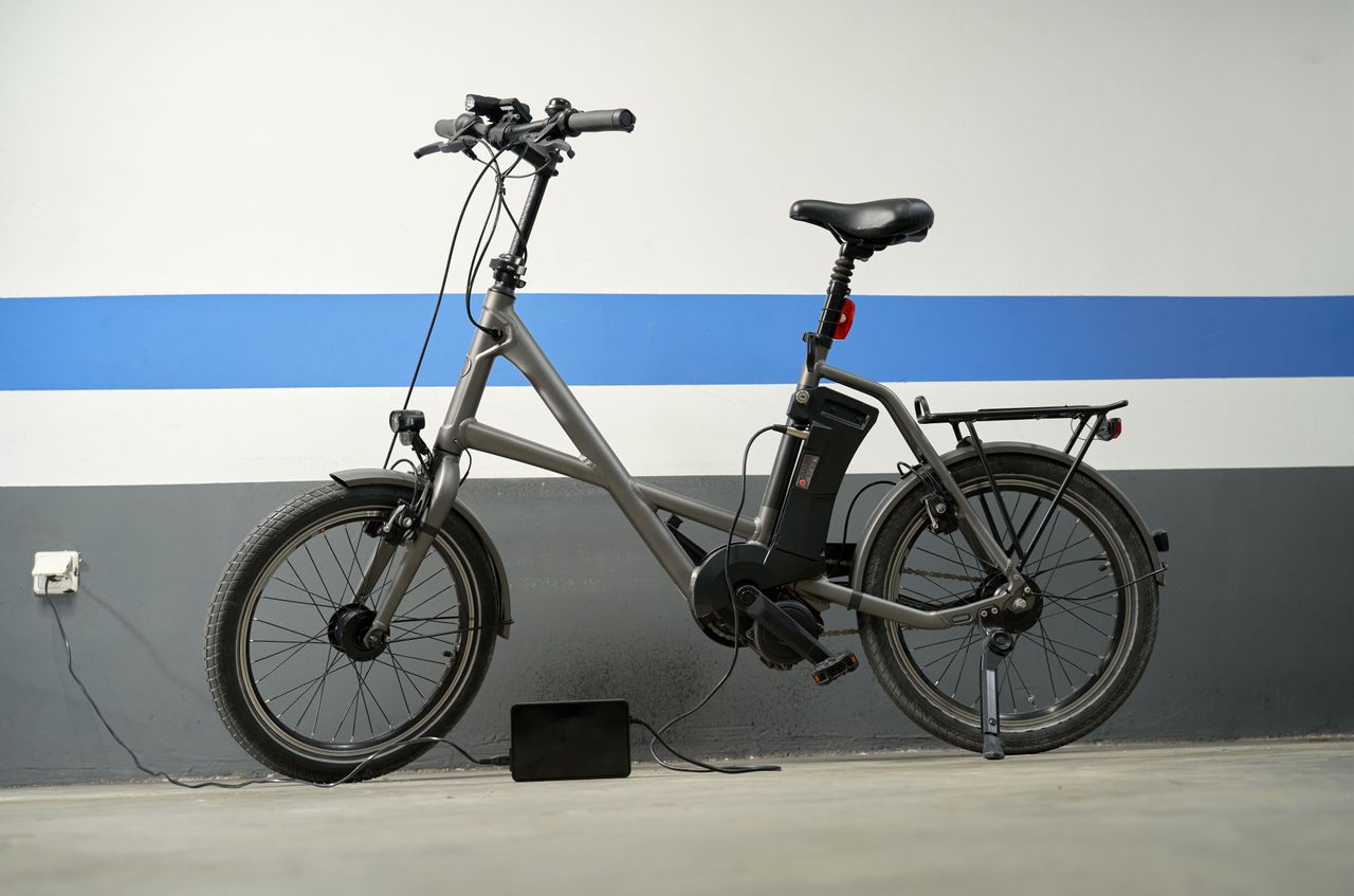 An e-bike leaning against a blue &amp; white wall as it charges