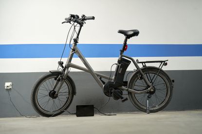 An e-bike leaning against a blue & white wall as it charges