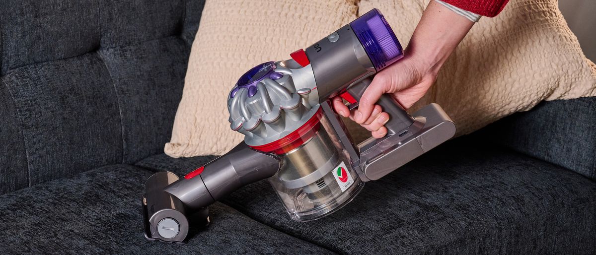 Person using the Dyson Car+Boat handheld vacuum on a sofa