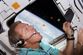 Since their first flight on STS-3, M&M's have become a favorite food item in space. Here, NASA astronaut Loren Shriver, STS-46 commander, pursues several of the chocolate-coated candies on the flight deck of the space shuttle Atlantis in 1992.