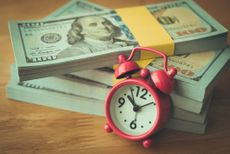 Alarm clock on stack US dollar banknotes.