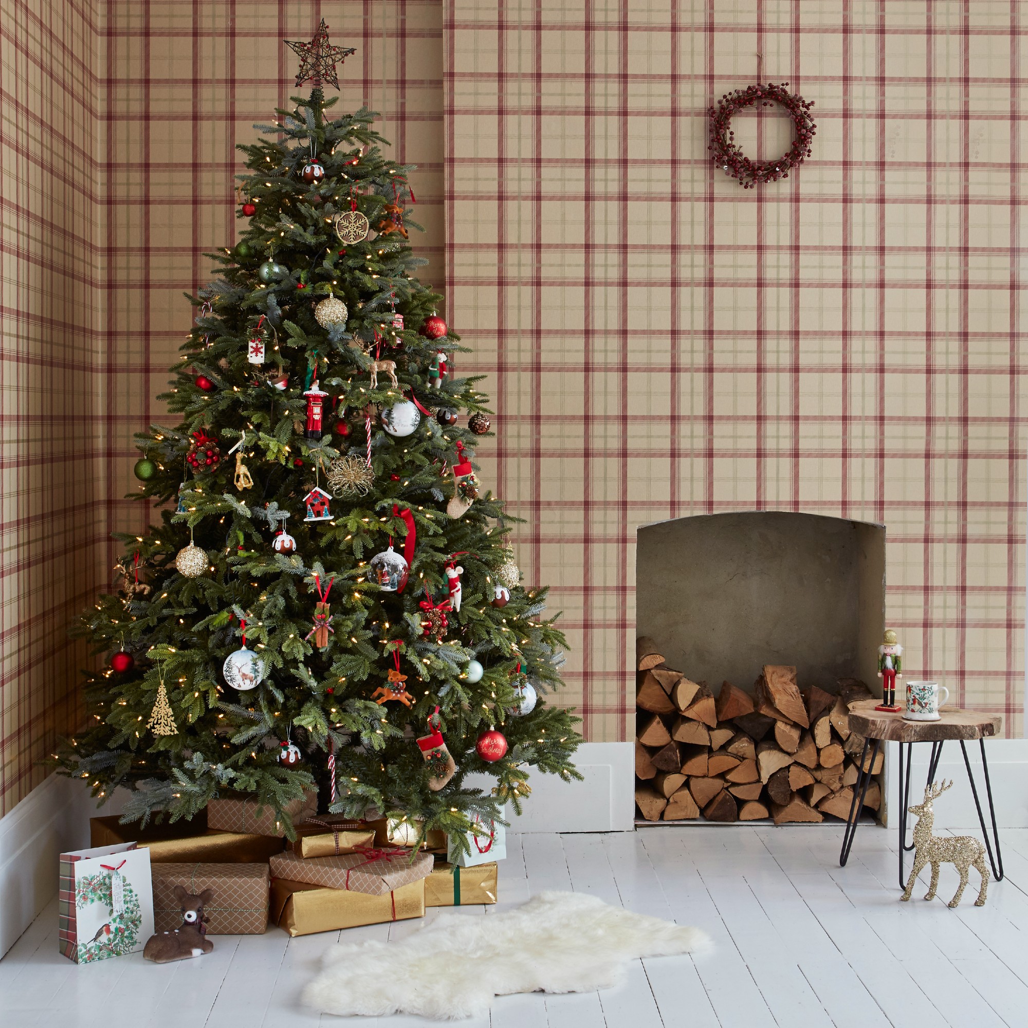 A room covered in a tartan-print wallpaper with a decorated, lit-up Christmas tree