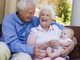 Grandmother and grandfather hold their infant grandchild.