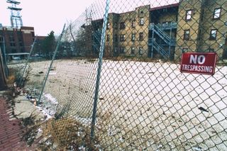 A photograph of the Oxford Apartments from behind a fence before they were demolished