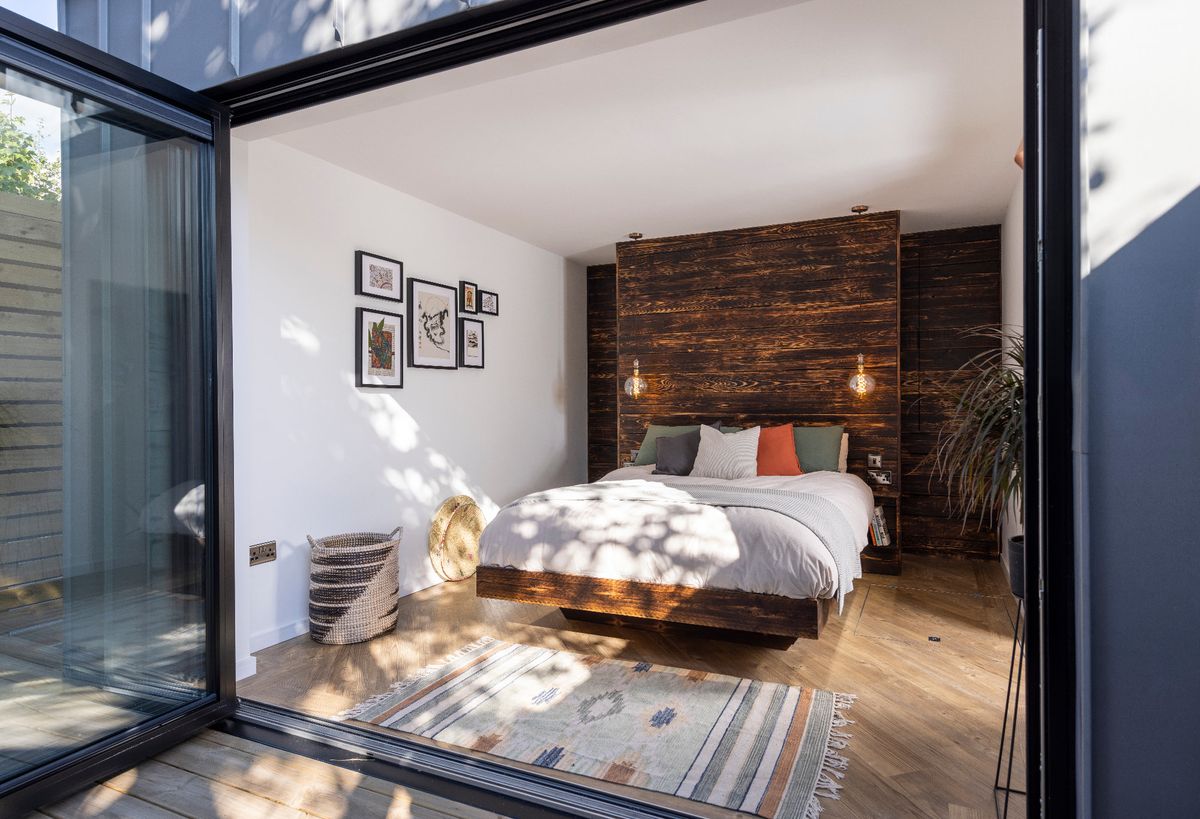 A bedroom in a self built container home with timber panelled walls