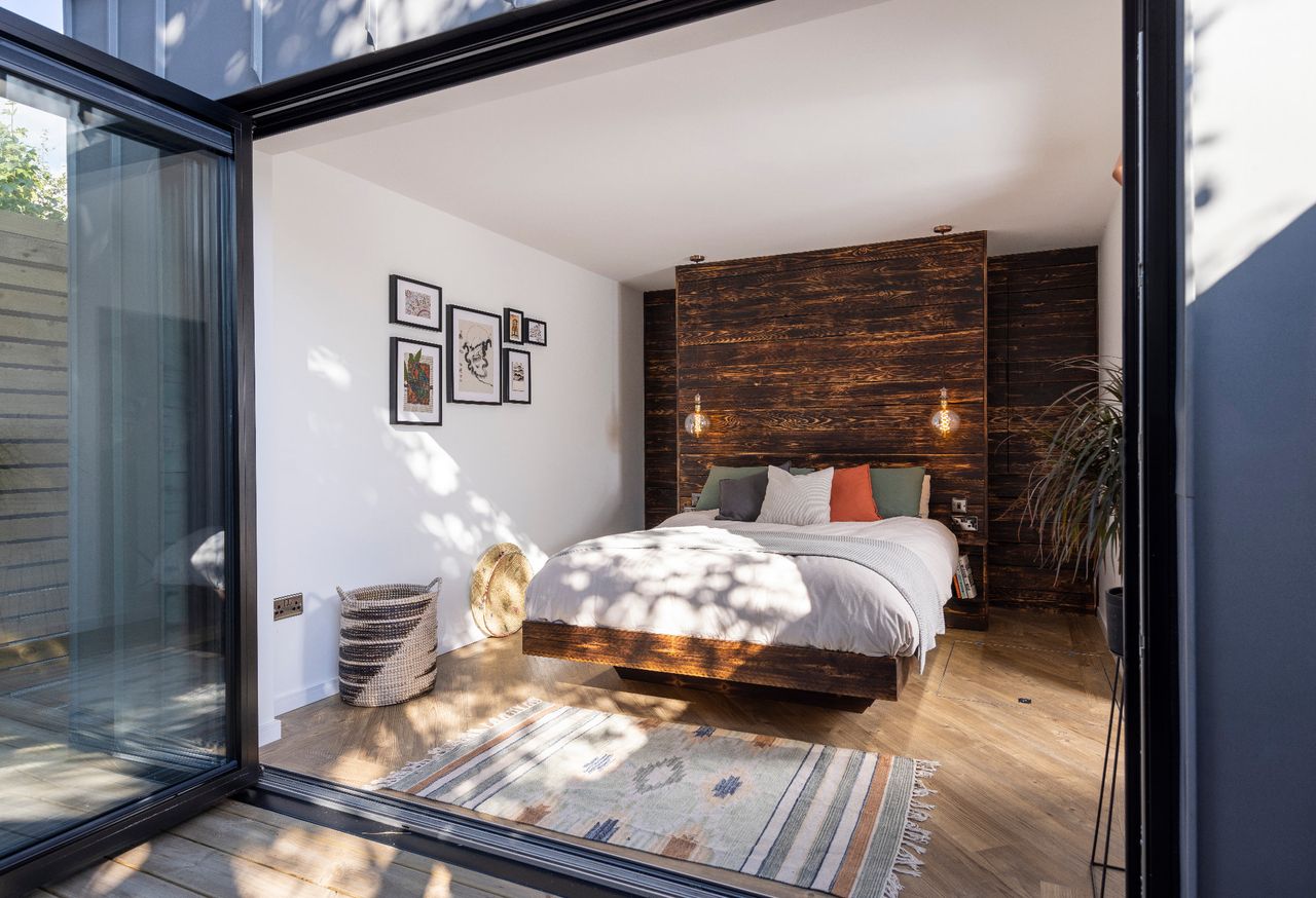 A bedroom in a self built container home with timber panelled walls