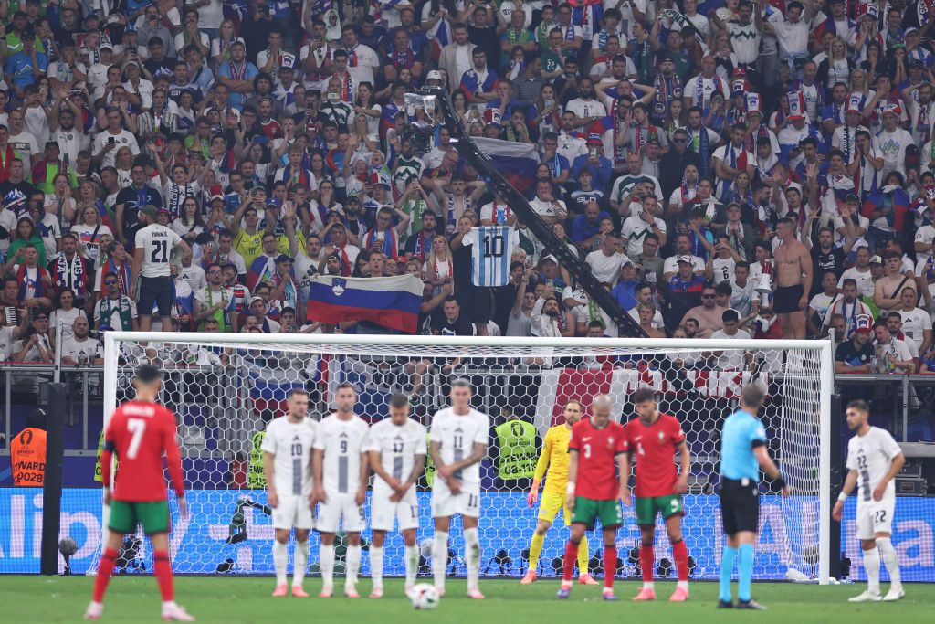 A Slovania fan holds up a Lionel Messi shirt as Cristiano Ronaldo of Portugal lines u[ a free kick during the UEFA EURO 2024 round of 16 match between Portugal and Slovenia at Frankfurt Arena on July 01, 2024 in Frankfurt am Main, Germany. (Photo by Robbie Jay Barratt - AMA/Getty Images)