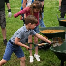 Princess Charlotte and Prince Louis shoveling dirt into a wheelbarrow