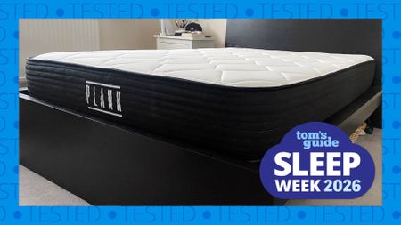 The Plank Firm mattress on a bed frame in our reviewer's bedroom. A blue border with the word 'tested' runs around the edge while a Tom's Guide Sleep Week graphic sits in the bottom right corner