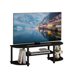 A TV on a black TV stand with decor on it