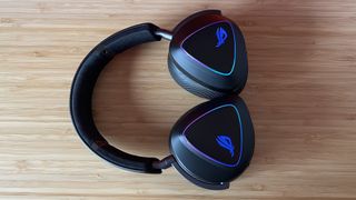 Asus ROG Delta II gaming headset with cups laid flat against a wooden desk