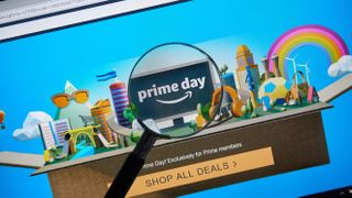 Amazon Prime Day landing page on a laptop monitor, with a magnifying glass held in front of the screen