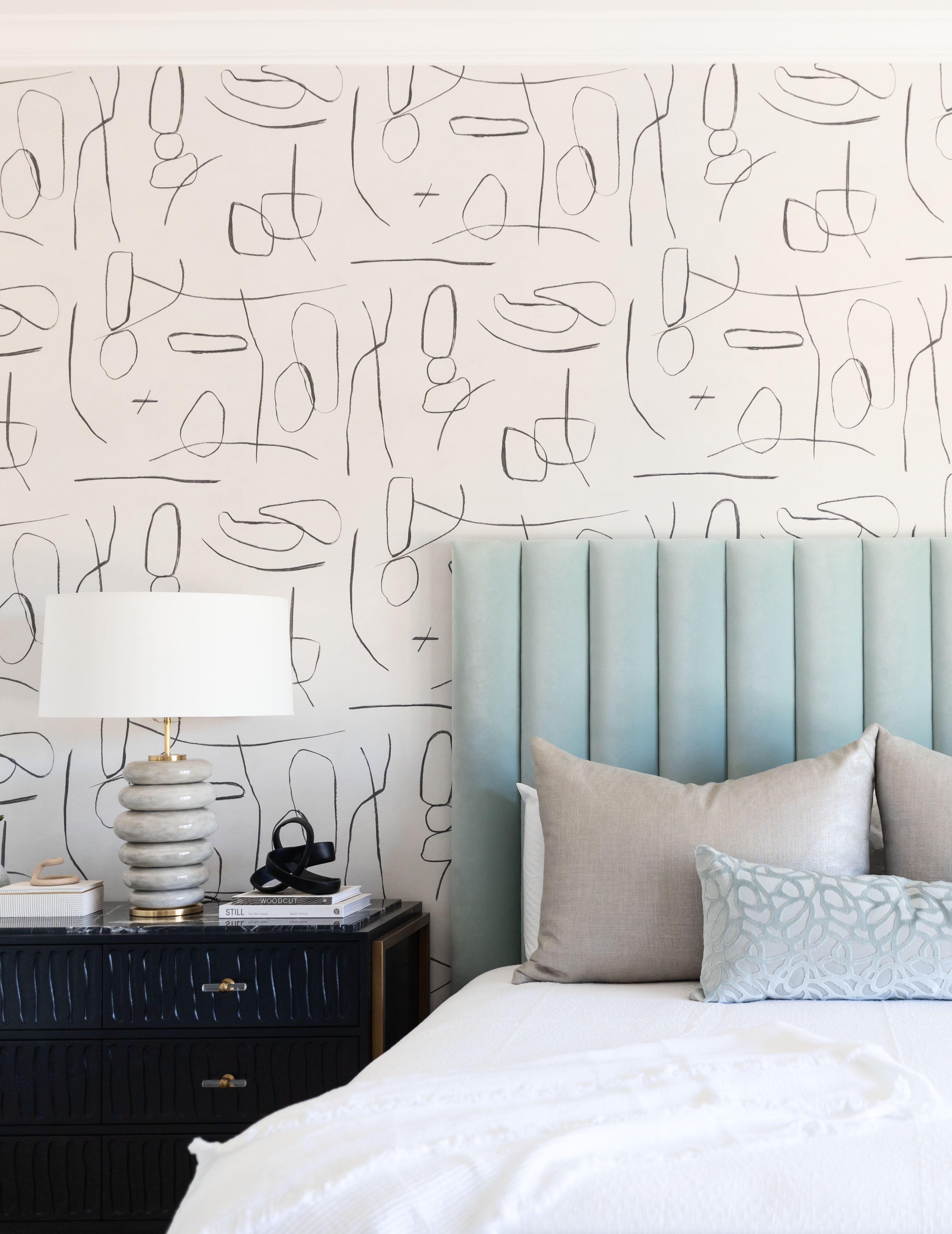 bedroom with linear wallpaper, pale blue headboard white table lamp