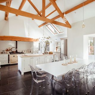 open kitchen with white wall and white dining table with glass chair