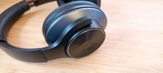 A pair of black and grey OneOdio A10 headphones sitting on a wooden desk