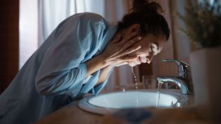 A woman washing her face at nighttime