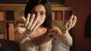 Rosa Salazar looks at her doll body arms while sitting up in bed in Alita: Battle Angel.