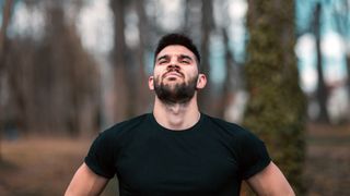 Man in woods taking deep breath in through his nose