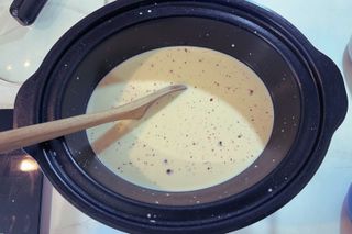 wooden spoon stirring hot chocolate in a slow cooker
