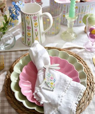 Easter table with gingham tablecloth, rattan placemat, green and pink plates and white linen napkin with bunny napkin ring