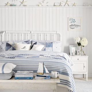 bedroom with white walls blue and white bedding and wooden floorboard